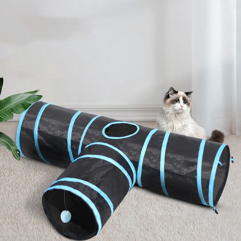 Cat playing with a black and blue striped tunnel on a carpeted floor.