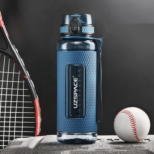 Blue water bottle with UZSPACE branding next to a tennis racket and baseball on a dark background